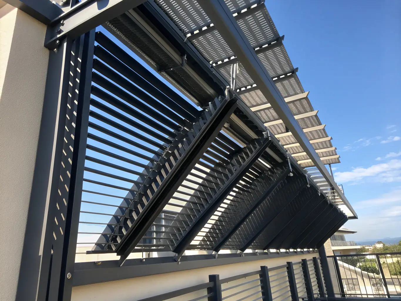 A close-up shot of the adjustable louvers of an Alu Business bioclimatic pergola, showcasing their ability to control sunlight and ventilation. The image should highlight the precision engineering and smooth operation of the louvers.